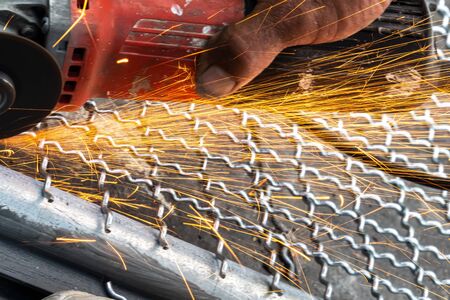 man used angle grinder without cover guard cutting metal net to make bird cage.の写真素材