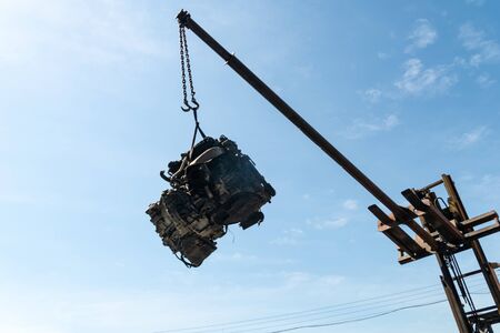 A forklift and workers are lifting an old car's engine for recycling.の写真素材