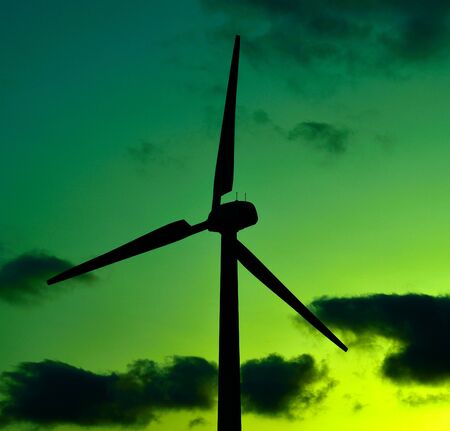 Wind turbine backlit on cloudy sky at dawn, colored imageの写真素材