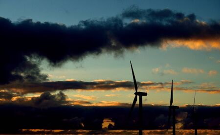Wind farm backlit with dramatic sky before sunriseの写真素材