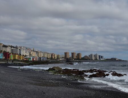 Rocky beach at low tide, city and cloudy sky, Las Palmas de Gran Canariaの写真素材