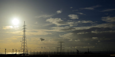 Industrial landscape at sunrise, splendid sky with clouds, high voltage towers and many wind...