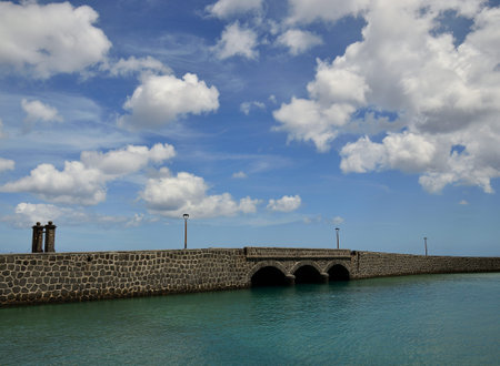 Stone bridge, sky with clouds and calm sea, coast of Arrecife, Lanzarote, Spain