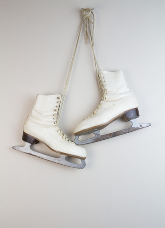 Old white ice skates hanging on the wallの写真素材