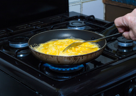 Scrambled eggs being cooked in pan over gas flameの写真素材