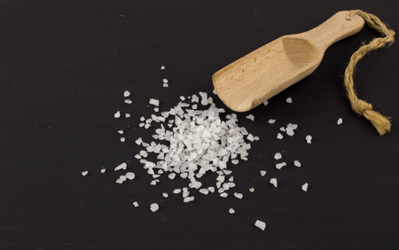 Salt isolated on black background closeup with wooden scoop - Space for textの写真素材