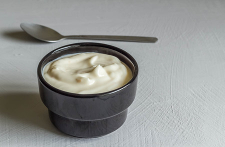 Yogurt in black cup on grey background with space for textの写真素材
