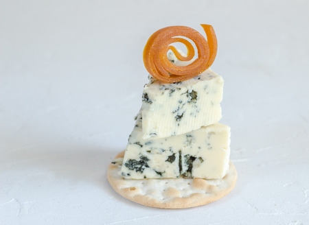 Blue cheese on cracker with dried apricot fruit curl decoration isolated on white backgroundの写真素材