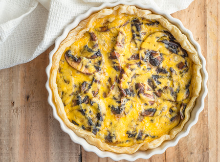 Mushroom quiche close up on wooden table - top view photoの写真素材