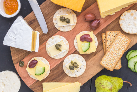 Cheese board with assorted cheese, and crackers on wooden board - top view photoの写真素材