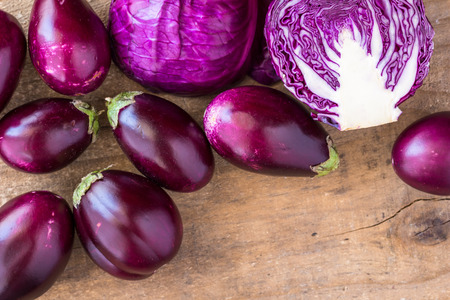 Baby aubergines and baby purple cabbage on rustic wooden surface with space for textの写真素材