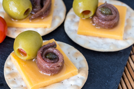Anchovy on crackers with stuffed olives - Appetizer background with selective focusの写真素材