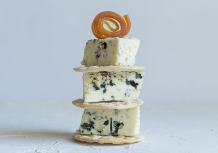 Blue cheese cubes on crackers stack close up side view photo on textured background