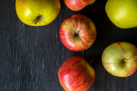 Red and green apples on a dark wood background - top view