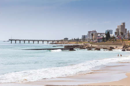 PORT ELIZABETH, SOUTH AFRICA - FEBRUARY 01 2020: View taken from Humewood beach towards Hobie beach with Shark Rock Pier, buildings and restaurants in background with old slipway built in 1903 in foregroundのeditorial素材