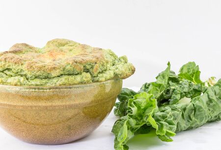 Cheesy cooked spinach souffle with fresh spinach on white table with copy spaceの写真素材