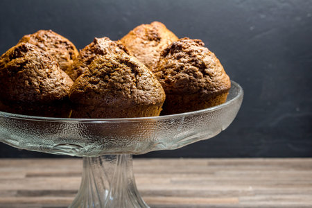 Delicious chocolate banana muffins in glass cake stand with copy space - baked chocolate muffin...
