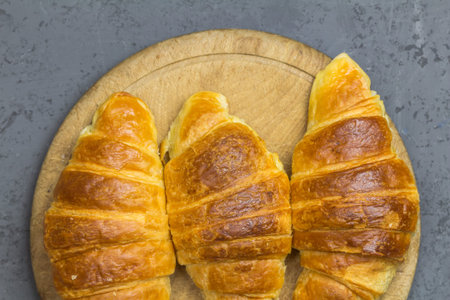 Three croissants on a wooden board - top view image close up