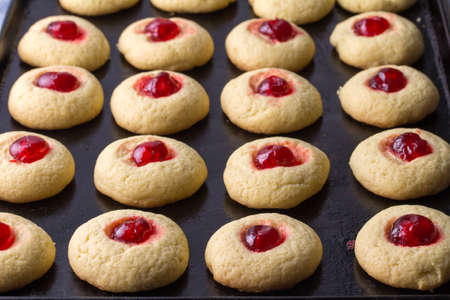 Cherry cookies on baking tray - delicious cherry topped cookie backgroundの写真素材