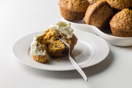 Carrot cinnamon cake muffin with yogurt on white serving plate with muffins in background isolated on white with copy space - close upの写真素材