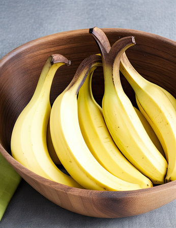 Bunch of bananas in a wooden bowl on a gray background.の素材