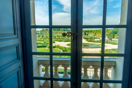 View of the Chateau de Versailles Gardens in Paris, France, through a window inside the palace