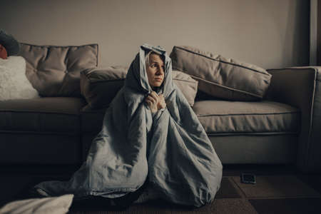 stop the war. Pray for Ukraine. we are available to Ukraine. Frightened Ukrainian woman is afraid of explosions, she hides under a blanket. The woman is afraid of the sounds of air raids and explosions. The concept of fear and sadness.の写真素材