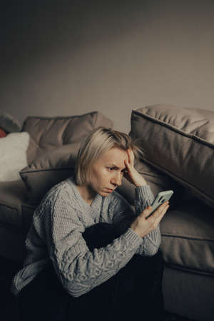 stop the war. Pray for Ukraine. we are available to Ukraine. Ukrainian frightened woman reads war news on her phone. The woman is afraid of the sounds of air raids and explosions. The concept of fear and sadness.の写真素材