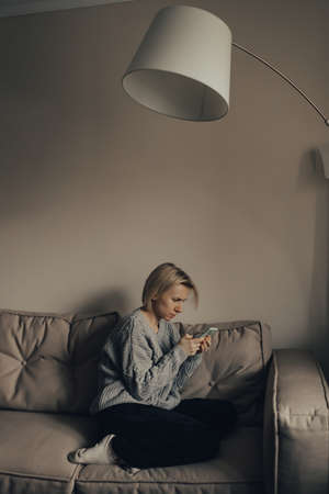 Ukrainian frightened woman reads war news on her phone. The woman is afraid of the sounds of air raids and explosions. The concept of fear. stop the war. Pray for Ukraine. we are available to Ukraine.の写真素材