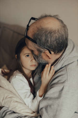 Ukrainian excited gray-haired man protects his little frightened granddaughter. Stop the war. Pray for Ukraine. We support Ukraine.の写真素材