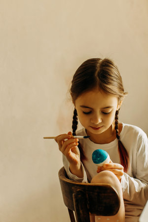 Portrait of a Ukrainian girl. the child paints the egg blue and yellow. The child loves and supports...