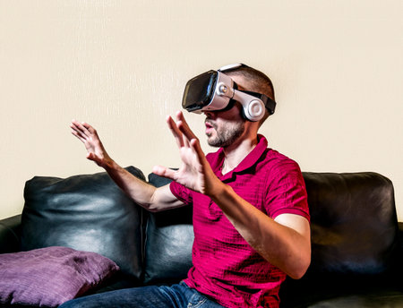 The man in glasses virtual reality plays  on the black sofa