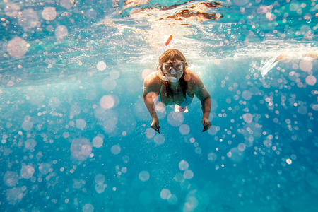 Girl swims under water with mask in blue seaの写真素材