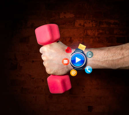 Sports smart watch with applications on the hand of the athlete holding a dumbbellの写真素材