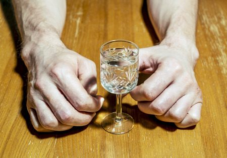 hands Men and a glass of vodka on the table before drinkingの写真素材