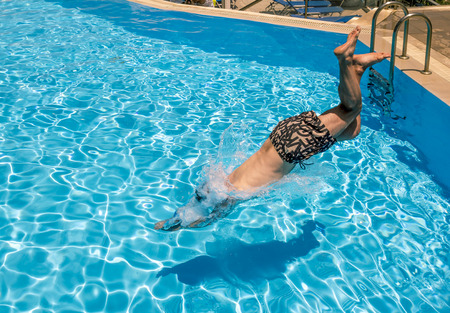 A man dives into the pool at the resort on a bright Sunny dayのeditorial素材
