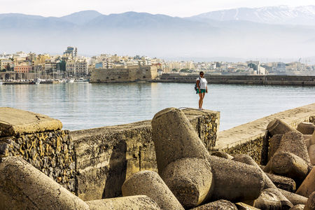 Heraklion.Greece.May 30, 2019. Girl standing on the breakwater against the fortress and ships in the port of Heraklion in Creteのeditorial素材
