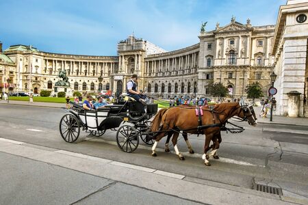 Vienna.Austria.August 29, 2019. Horse-drawn carriages with coachmen ride tourists at the Hofburg Palace complex in Vienna.のeditorial素材