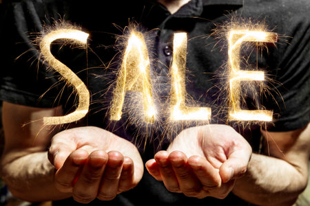 A man holds a sparkling sale sign on a dark backgroundの写真素材