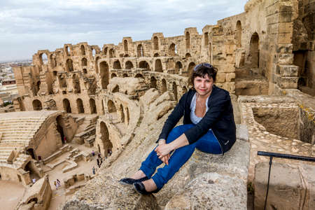 El Jam.Tunisia.May 21, 2013.A girl poses against the backdrop of the Roman amphitheater in the city of El Djem in Tunisia.のeditorial素材
