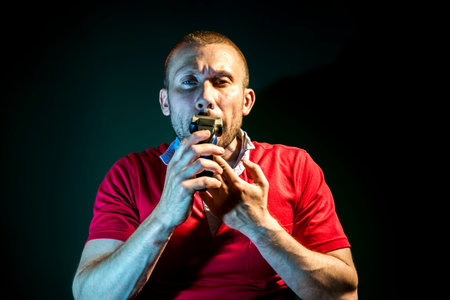 Man shaving with electric razor on dark green background