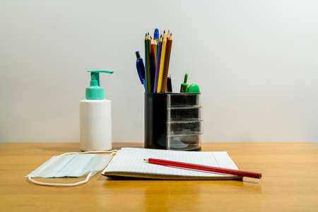 On the table are school supplies, along with an anti-virus mask and sanitizer.Back to school.の写真素材