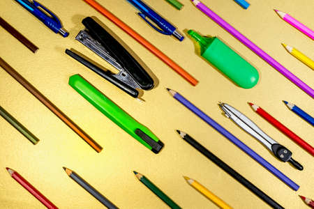 Stationery and multicolored pencils are arranged diagonally on a Golden surfaceの写真素材