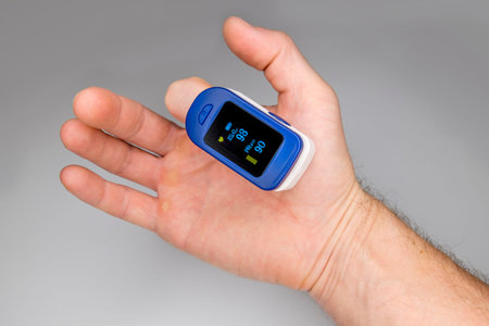 A pulse oximeter on the finger of a man's hand measures the amount of oxygen in the blood and the...