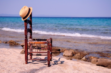 Old chair with a hat at the beachの写真素材