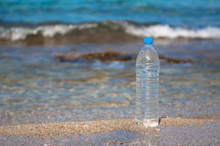 Bottle of natural water placed at the beach near the seaの写真素材