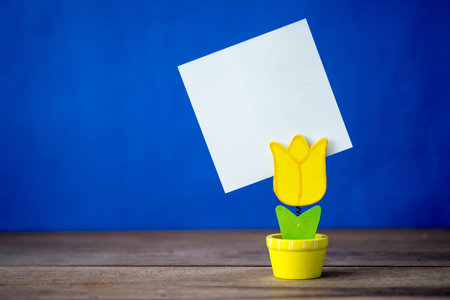 Flowerpot model of note clip on the wood table and blue background.の写真素材