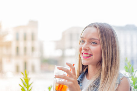 Happy young girl drinking a cocktail outdoor, during a sunny summer day