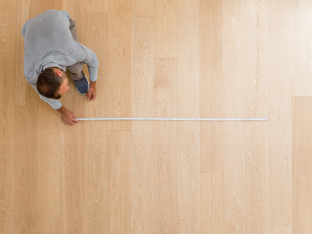 Architect taking measures of the new hardwood floor. Home and maintenance conceptsの写真素材