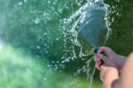 Kid playing with water sprinkler in the gardenの写真素材